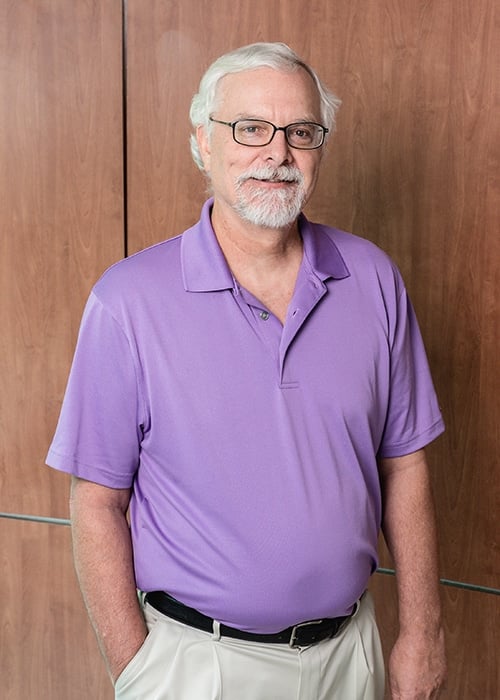 a man wearing glasses and smiling at the camera