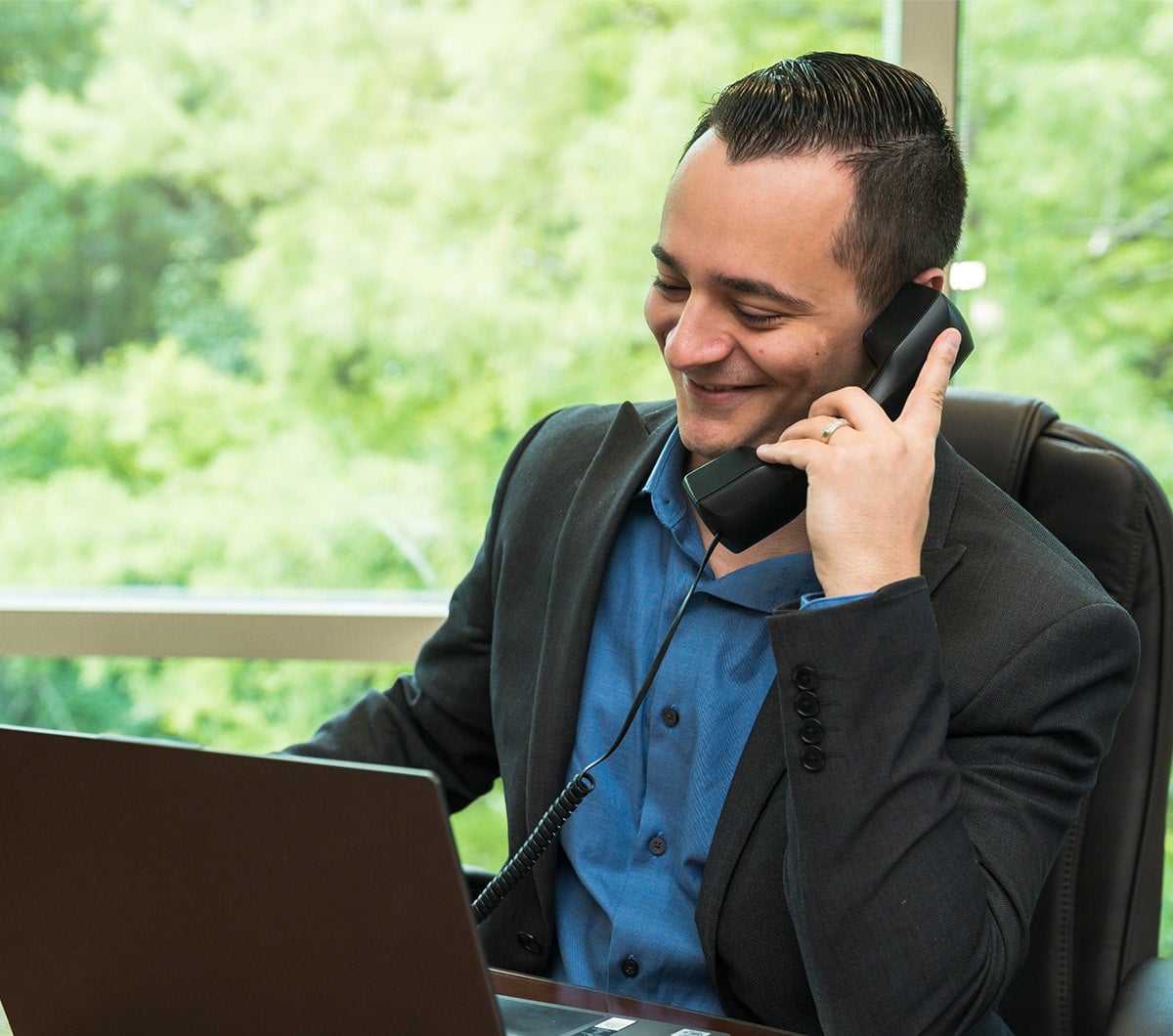 a man using a laptop computer talking on a cell phone